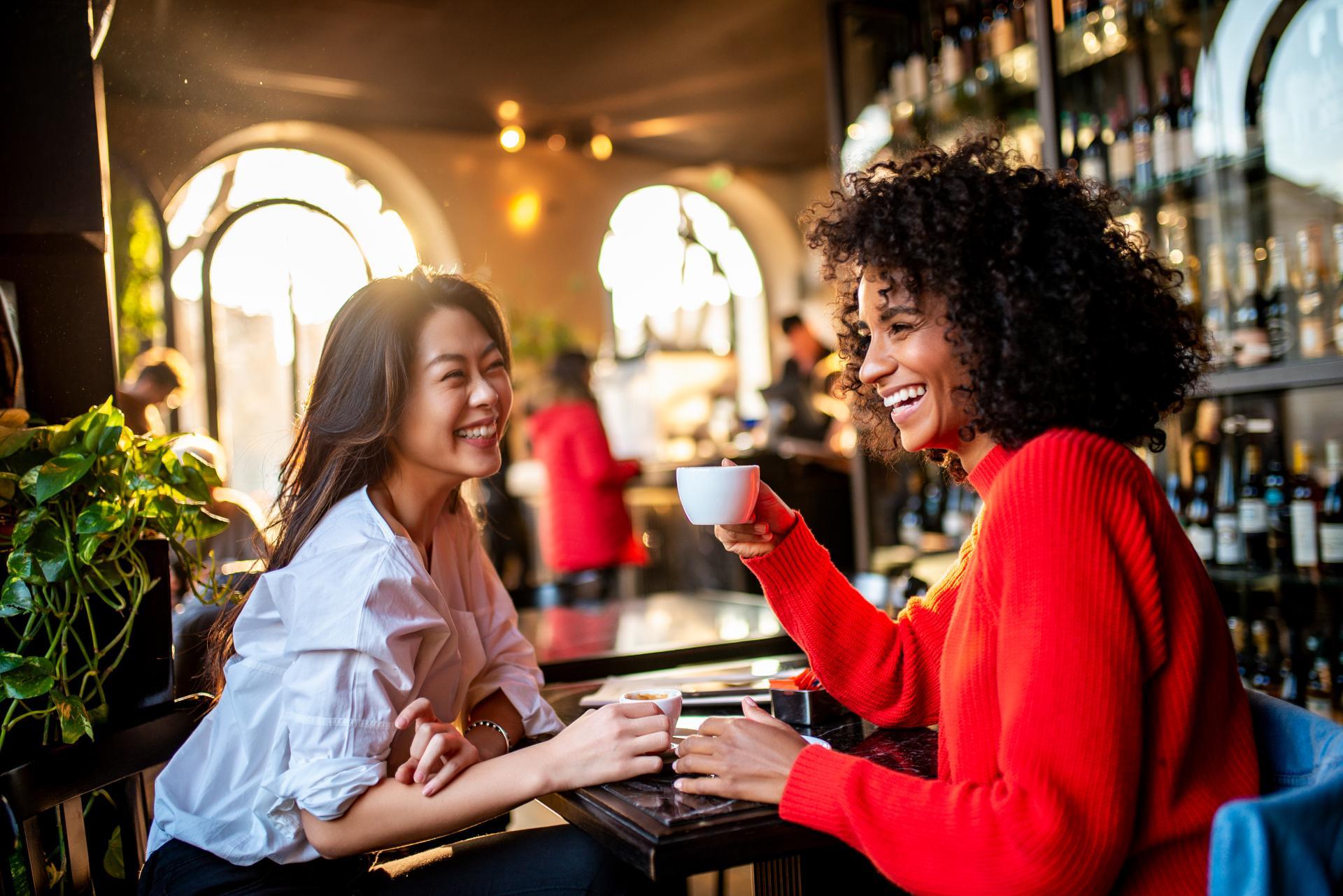 Two well-dressed smiling women enjoying an espresso in a lounge area